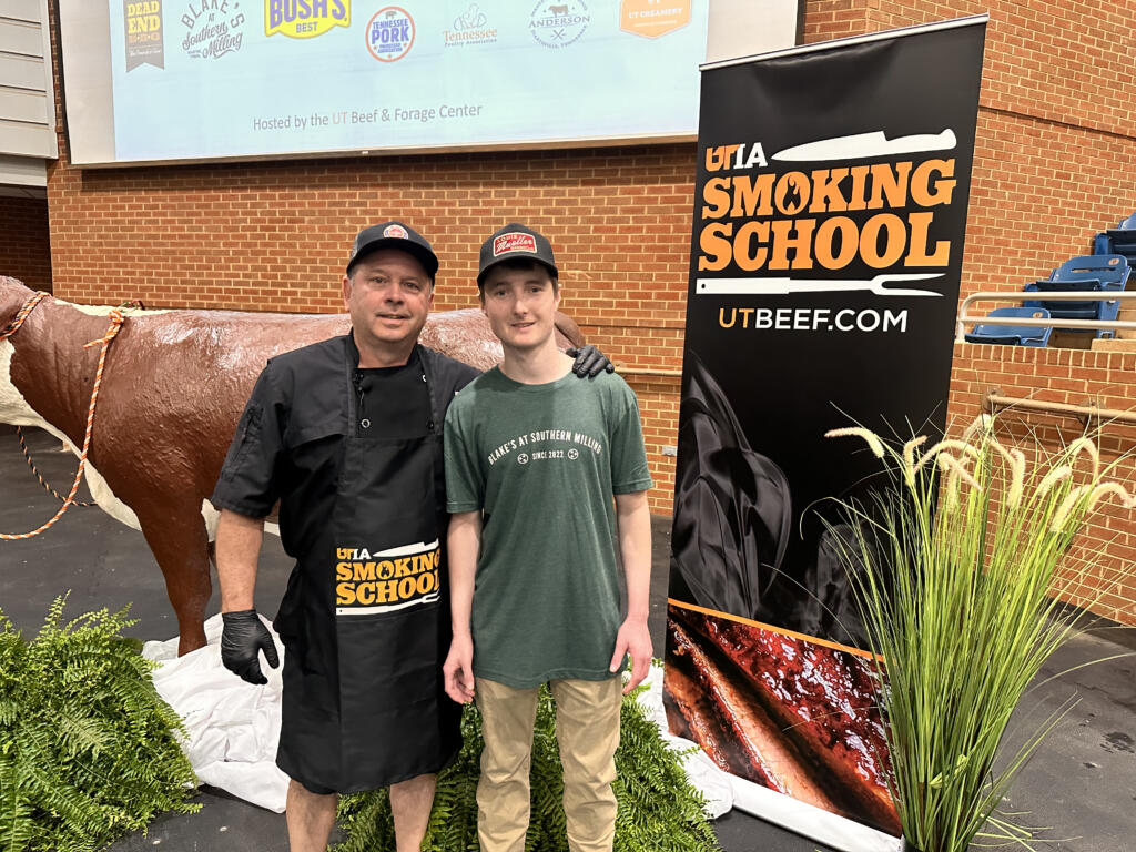 the university of Tennessee Knoxville's smoking school guest pitmaster, George Ewart, with a UTK student.